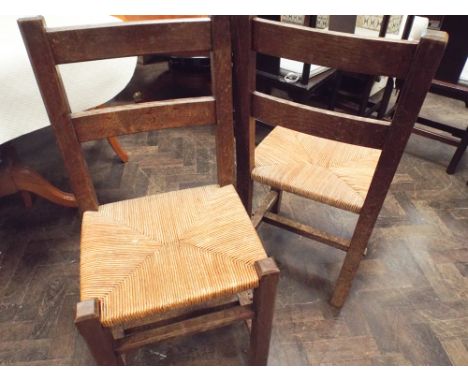 A pair of oak ladder back style dining chairs with rush seats 