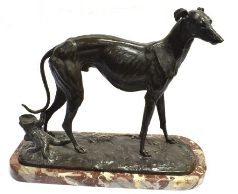 A PATINATED SPELTER FIGURE OF A LURCHER  naturalistically modelled standing beside a tree trunk, on oval base 34cm high 40cm 