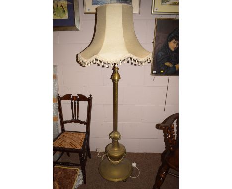 An early 20th Century brass standard lamp, lion mask mounts, on circular plinth base.
