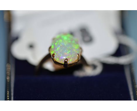 A n opal ring, the oval opal cabouchon claw set on a yellow metal shank, stamped 9ct, ring size O.