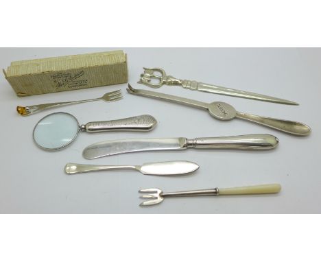 A silver handled magnifying glass, two silver forks, a silver butter spreader, a letter opener, etc. 
