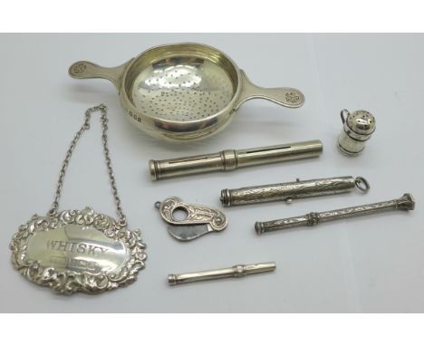 A silver whisky label, a silver strainer, four pencils, a small silver pepper and a silver cutter 