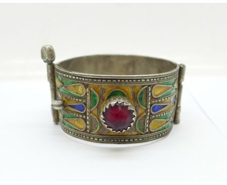 An enamelled white metal bangle set with two red stones, some enamel a/f 