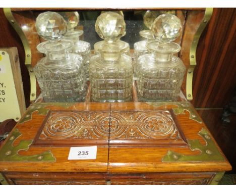 An oak three bottle tantalus with multi section compartment and secret drawer (with key)