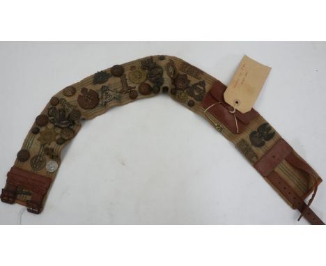 Collection of WWII cap, collar and shoulder badges with uniform buttons affixed to a leather and canvas belt, believed to hav