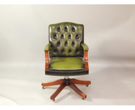 A mahogany and button back green leather swivel office chair, raised on a metal column and five flanked cabriole legs, on cas