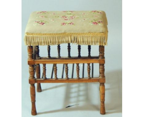 A Victorian oak stool, with floral woolwork tapestry seat, raised on turned legs united by a spindle bottom and turned galler