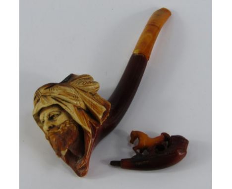 A Meerschaum pipe and a cheroot holder, the pipe carved with the head of an Arab, amber tipped, cased, 15.5cm long, the chero