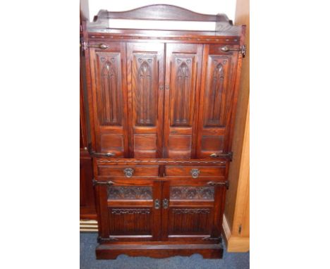 An Old Charm oak television cabinet, the galleried top above a pair of doors carved with gothic tracery, pair of frieze drawe