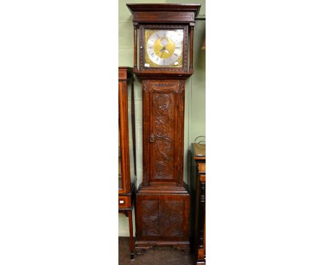 An oak carved thirty hour longcase clock, brass dial with silvered recessed plaque inscribed Monkhouse, Carlisle, later case