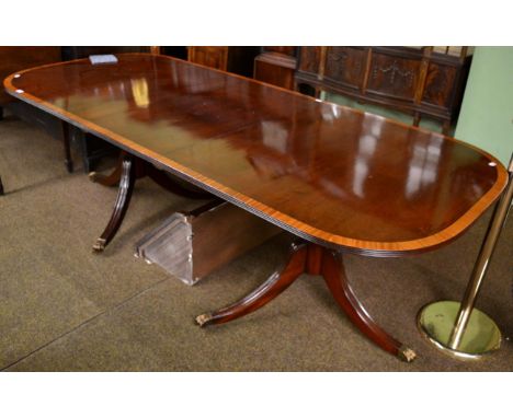 A reproduction mahogany, satinwood banded and boxwood strung twin-pedestal dining table in Regency style, with one additional