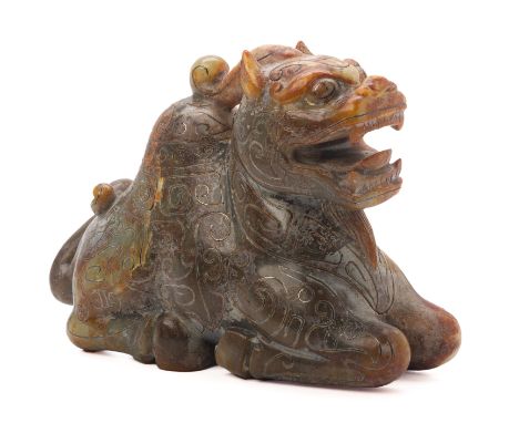 A CARVED JADE MODEL OF A MYTHICAL BEAST
Of archaic style, modelled in a recumbent position with its legs tucked beneath its b