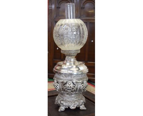 An electro-plated table oil lamp, pierced and profusely embossed in the Rococo taste with leafy scrolls, etched fluted shade,