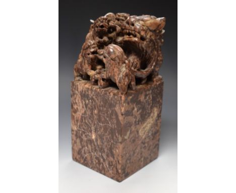 A large Chinese soapstone scroll weight, carved with a foe dog and its progeny, the side panels each with a magnolia flower, 