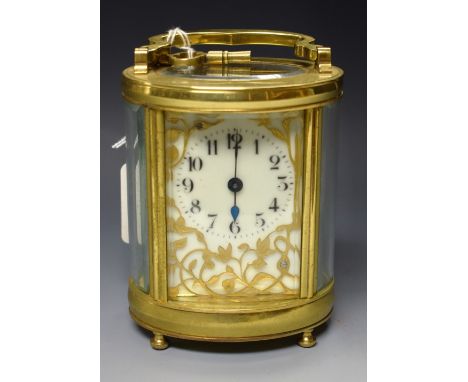 An early 20th century oval carriage clock, white dial, ornate brass floral decoration, manual movement, folding handle