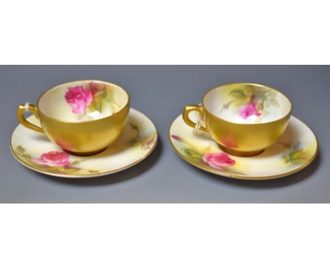 A pair of Royal Worcester cabinet cups and saucers, painted by M Hunt, one signed, with pink and red cabbage roses, gilt exte