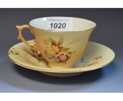 A Royal Worcester teacup and saucer, printed and painted with spring flowers on a blush ivory ground, gilt line borders, prin