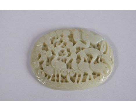 A CHINESE CARVED AND PIERCED JADE OVAL PLAQUE, depicting cranes and foliage, 7cms x 5.5cms.