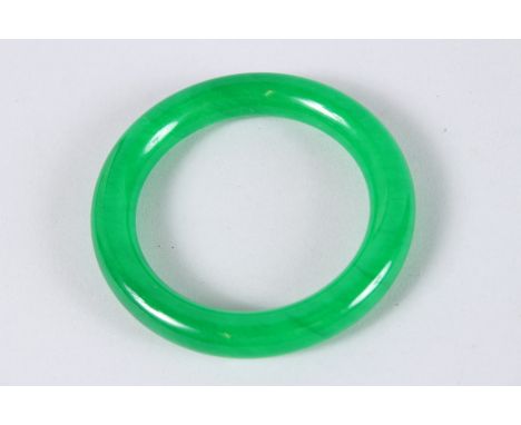 A CHINESE APPLE GREEN JADE BANGLE. 3.25ins diameter.