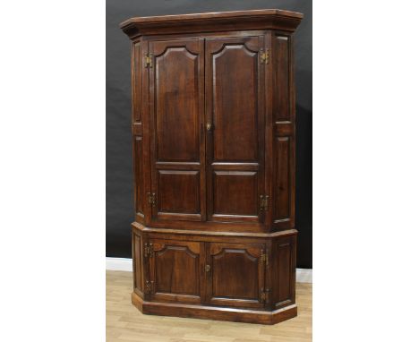 A 19th century oak country house floor-standing splay-fronted corner cupboard, outswept cornice above a pair of panel doors e