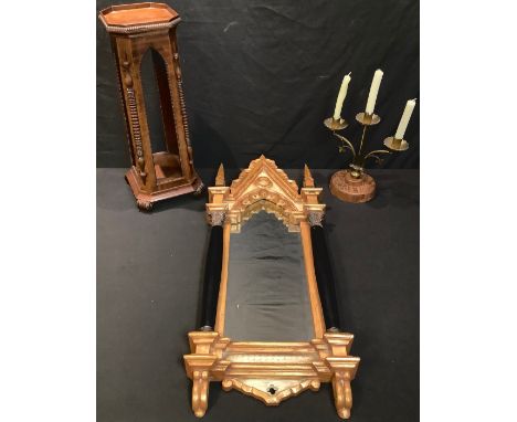 An early 20th century Moorish inspired mahogany statuary pedestal, 57cm high; a Gothic style wall mirror; a brass altar candl