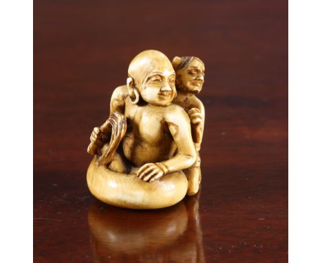 A JAPANESE IVORY NETSUKE, 19th Century, carved as an immortal half submerged in a hibachi serving as a bath while an oni scru