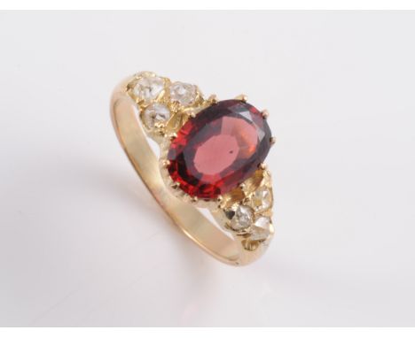 A LATE 19TH CENTURY ALMANDINE GARNET AND DIAMOND RING, the oval cut almandine garnet claw set between moulded tapering should
