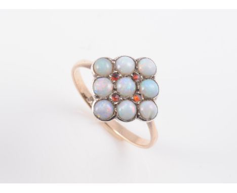 AN OPAL RING, the square shaped mount set with nine round cut opal highlights in a simple open detail mount between solid tap