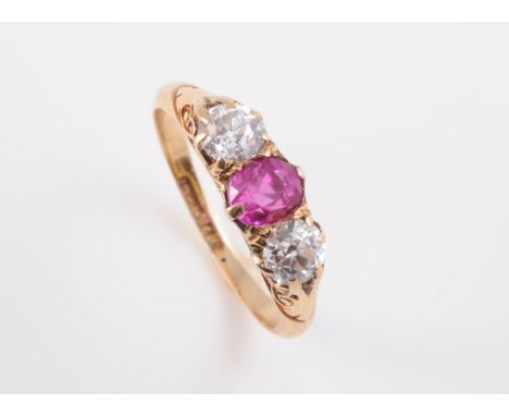 A LATE VICTORIAN RUBY AND DIAMOND RING, the oval cut ruby set between two old brilliant cut diamonds in a subtle pierced and 