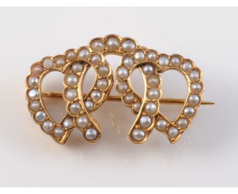A LATE 19TH CENTURY SEED PEARL SET BROOCH, modelled as a horse shoe intertwined between two witches hearts, all set throughou