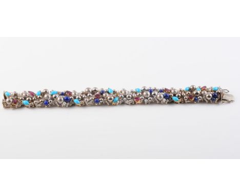 AN 18CT WHITE GOLD, NATURAL RUBY, TURQUOISE AND LAPIS LAZULI BRACELET BY STUART DEVLIN, the abstract bracelet of graduating g
