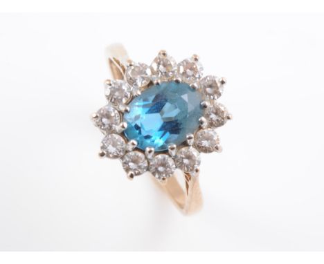 AN AQUAMARINE AND DIAMOND RING, the oval cut aquamarine claw set within a surround of twelve brilliant cut diamonds, in a pie