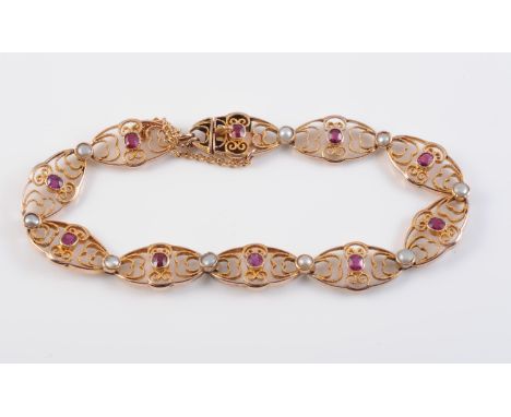 A 9CT YELLOW GOLD, RUBY AND SEED PEARL BRACELET, circa 1900, formed of ten oval links of delicate scrolling metal work, set t