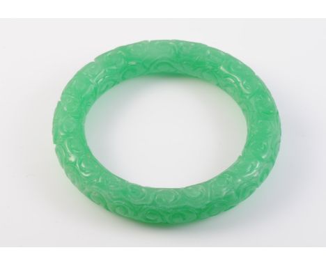 A JADEITE BANGLE, carved to the entirety. Diameter 8.2cm. Weight 85.1gms.
