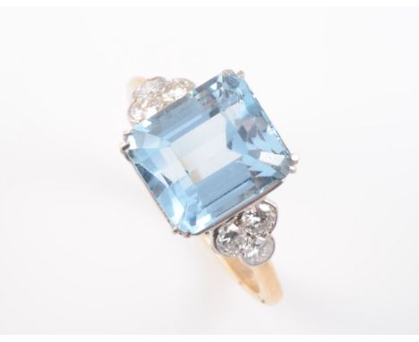 AN AQUAMARINE AND DIAMOND RING, the square cut aquamarine four double claw set, raised between moulded scalloped shoulders ea