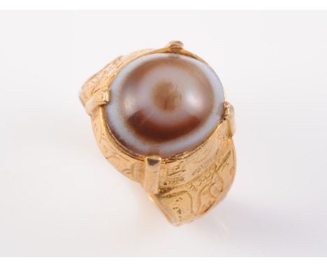 A GEORGIAN AGATE RING, the heavy band with engraving to the entirety, set with an oval cabochon cut banded agate in similarly