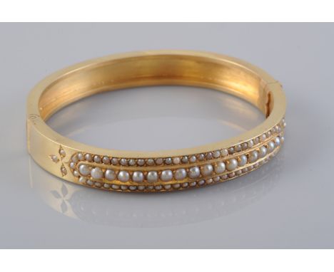 A LATE 19TH CENTURY SEED PEARL SET BANGLE, the central row of uniform seed pearls set slightly raised within a surround of sm