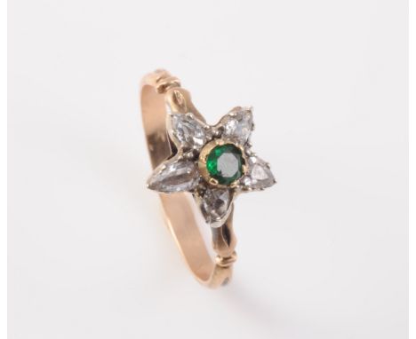 A LATE 19TH CENTURY DIAMOND AND EMERALD RING, the flower head shaped mount set to the centre with a single round cut emerald 