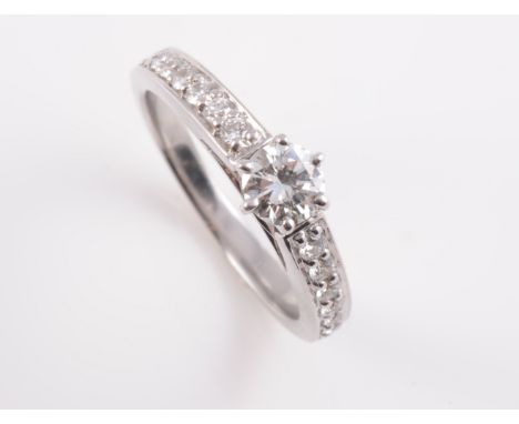 A DIAMOND RING, the brilliant cut diamond six claw set in a raised mount between pierced shoulders and a tapering band each s