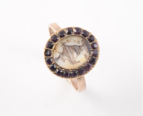 A GEORGIAN MEMORIAL RING, the oval mount set with a pencil drawing of an urn, within a surround of mixed cut amethyst highlig