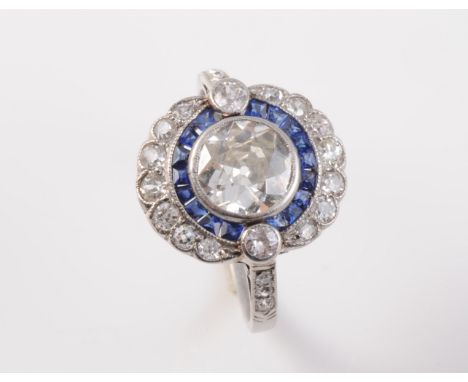AN ART DECO SAPPHIRE AND DIAMOND RING, the large brilliant cut diamond collet set within a moulded mount of subtle scalloped 