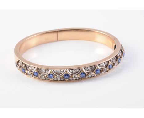 A LATE 19TH CENTURY SAPPHIRE AND DIAMOND BANGLE, the eleven cushion cut sapphires each set in pierced cut out mounts within s