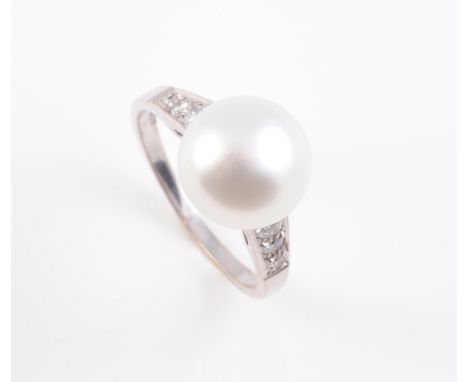 AN 18CT WHITE GOLD, CULTURED PEARL AND DIAMOND SET RING, the large cultured pearl set raised between pierced tapering shoulde