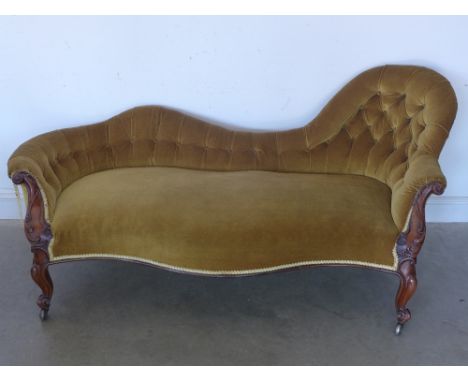 A Victorian button back mahogany chaise longue - with carved arms and shaped legs, terminating in casters 