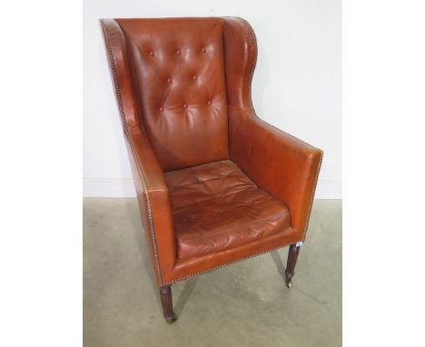 A 19th century leather upholstered button back library chair on turned reeded front legs and brass casters