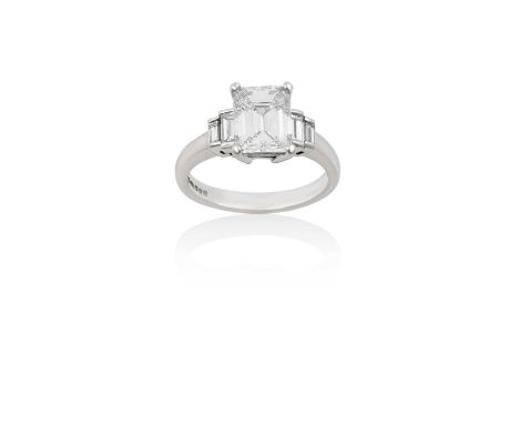 A Platinum Diamond Ring the central emerald-cut diamond flanked by graduated pairs of baguette cut diamonds, in white claw se