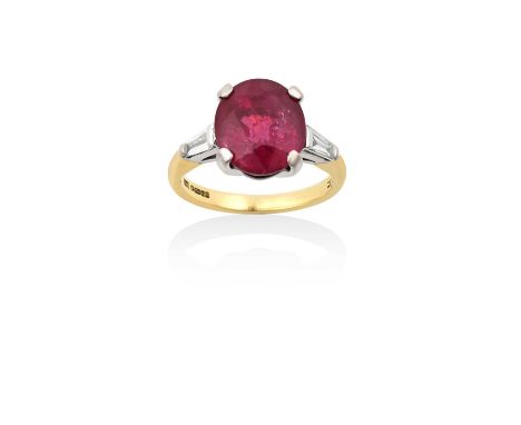 An 18 Carat Gold Ruby and Diamond Ringthe oval cut ruby flanked by tapered baguette cut diamonds, in white claw settings, to 