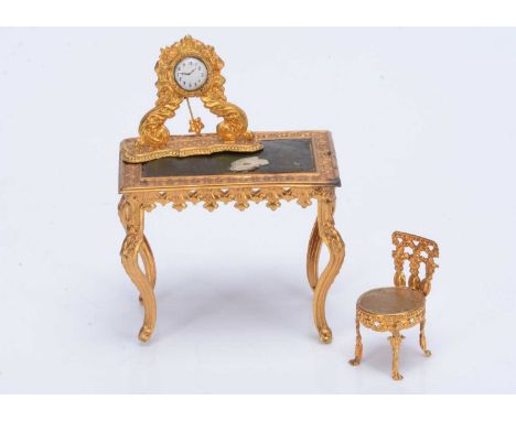 German gilt metal  dolls’ house items,  a table with leather top —2 ½in. (6.5cm.) high (piece of paper stuck to leather, mayb