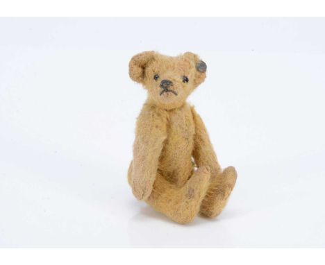 A Steiff miniature teddy bear, circa 1910, with golden mohair, black bead glass eyes, black stitched nose and mouth, FF under