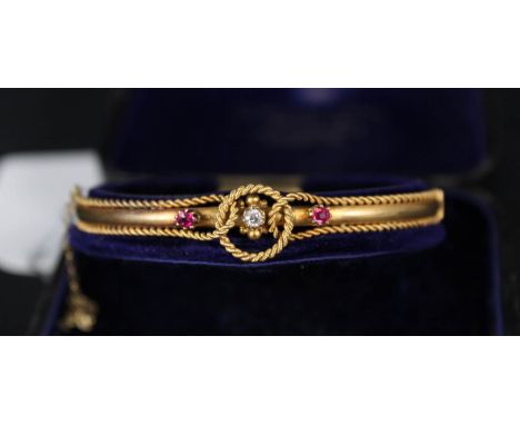 A 15ct gold bangle with rope decoration set with central diamond flanked by rubies either side